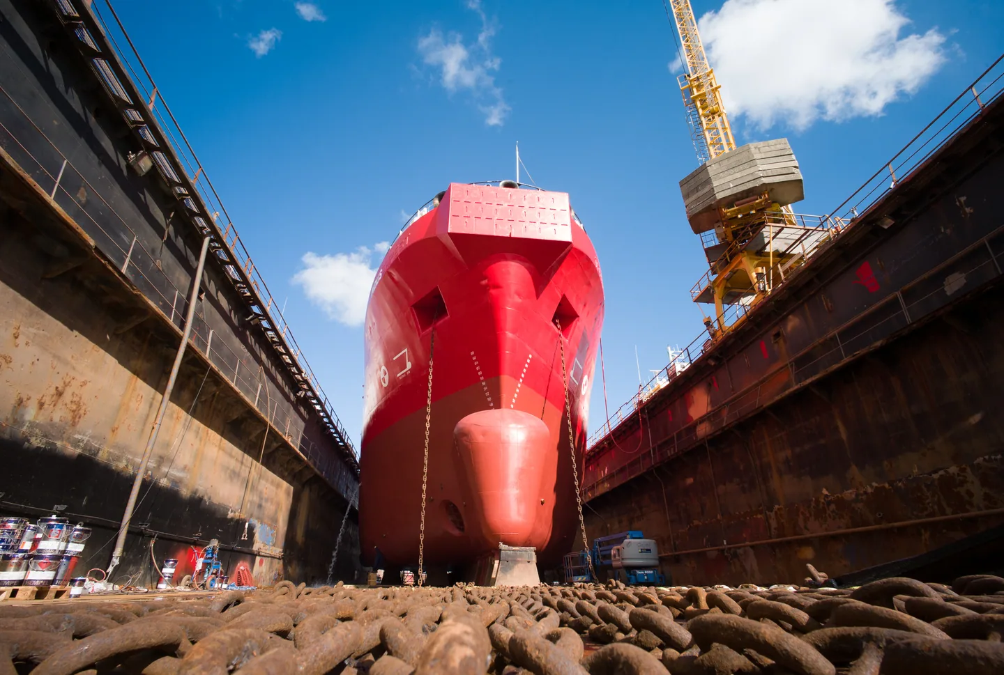 The bow of a ship in dry dock beneath a shipyard crane.