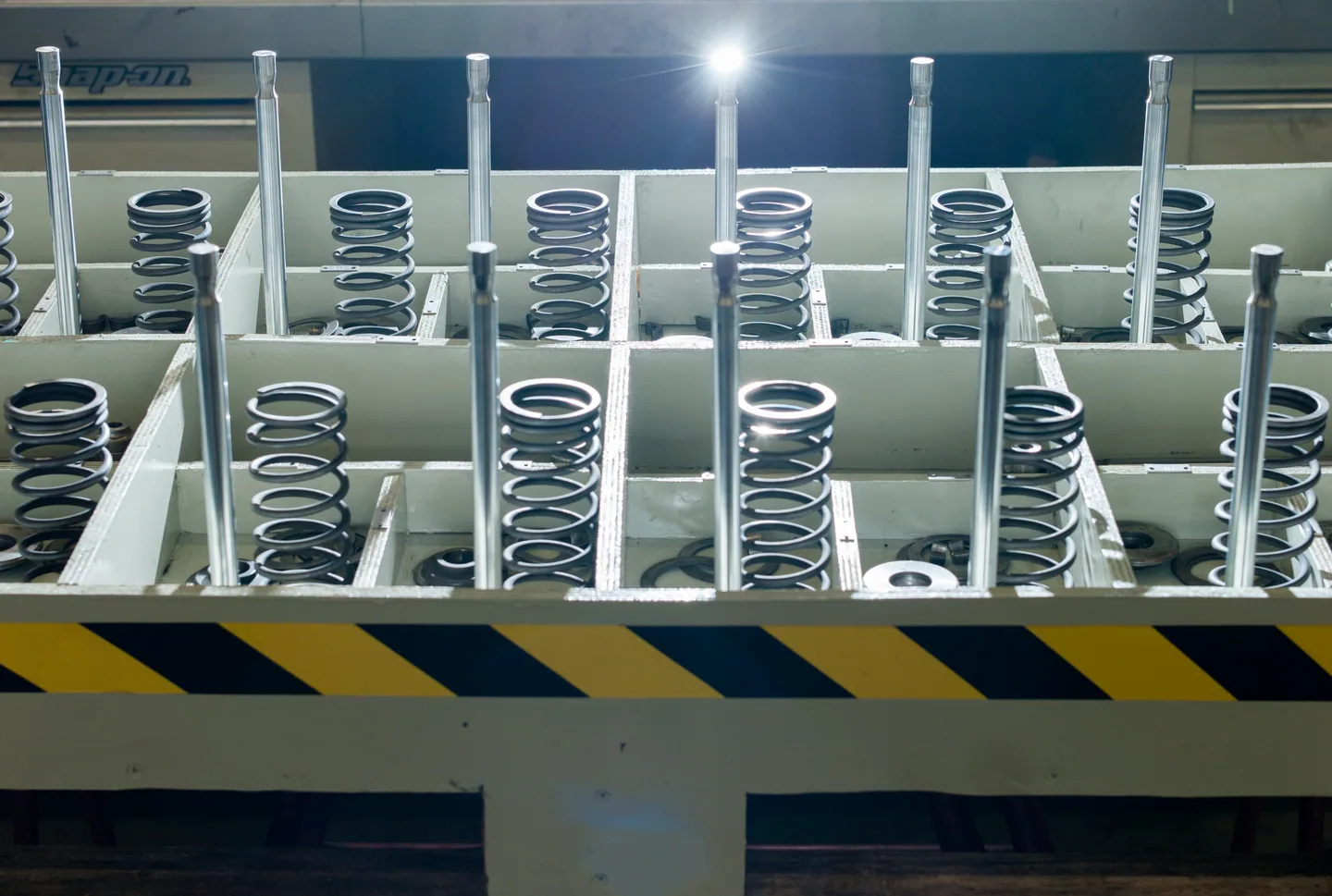 Engine valves and springs arranged in a workshop rack.